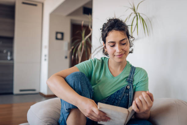 istock Happy girl enjoying while reading a book at home 1354681730