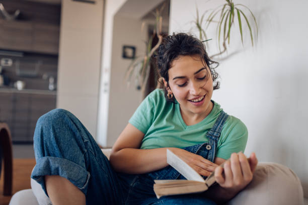 istock Happy girl enjoying while reading a book at home 1354681736