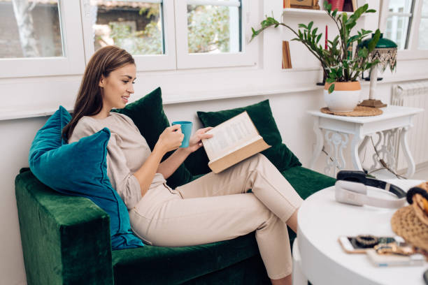 istock Young woman reading a novel and enjoying coffee 1354681824