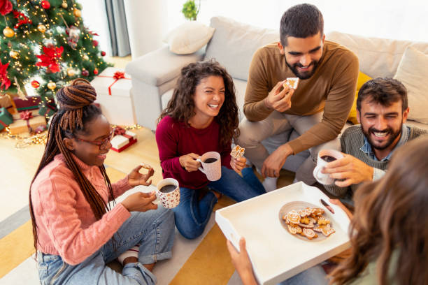freunde, die weihnachten zu hause verbringen, lebkuchenkekse essen und kaffee trinken - communication discussion coffee christmas stock-fotos und bilder