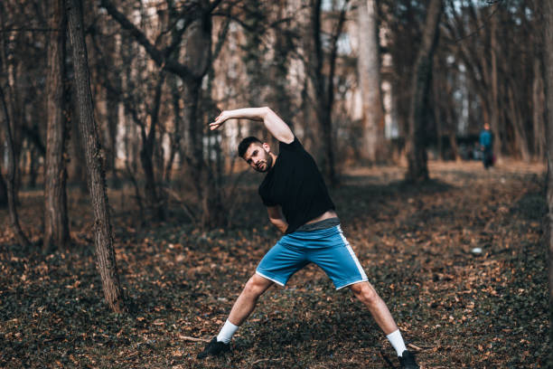 istock Sporty man stretching exercise for warming up before running in the park or gym workout. Fitness and healthy lifestyle concept. 1354683642