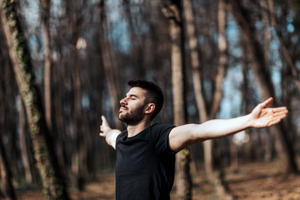 istock Young man breathing fresh air stretching arms in a park 1354683682