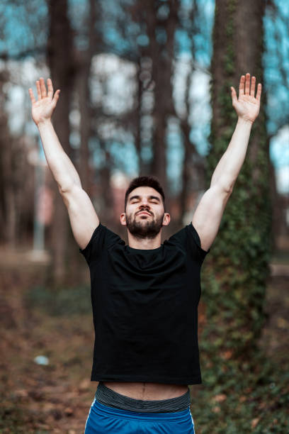 istock Young man breathing fresh air stretching arms in a park 1354683683
