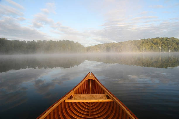 Journey by Cedar Canoe Bow of a cedar canoe being paddled on a northern Ontario lake northern ontario stock pictures, royalty-free photos & images