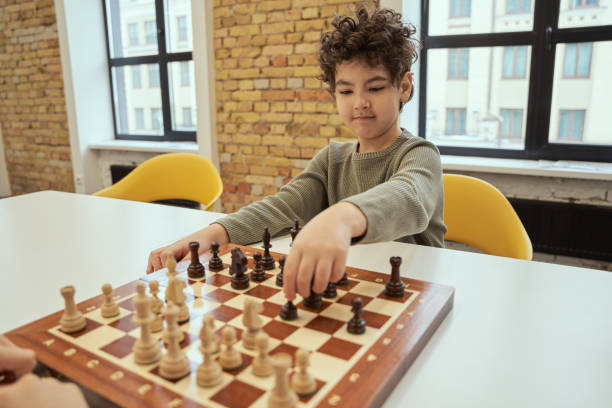 istock Good move. Observant little boy making a move while sitting in the classroom and playing chess on the chessboard 1354688202