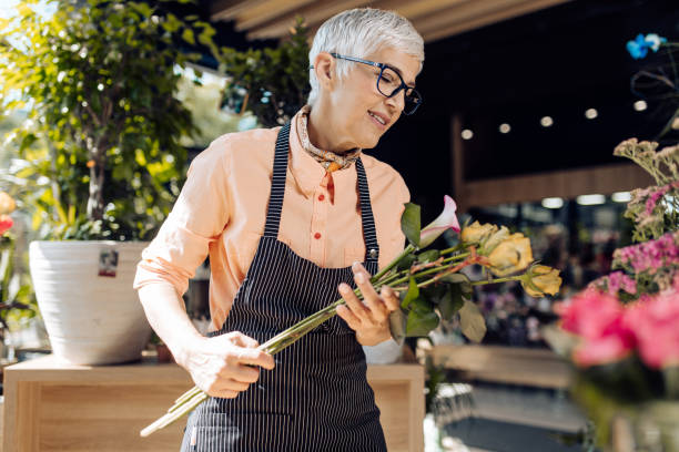 istock Mature florist making a bouquet with sunflowers 1354688716
