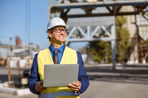 istock Joyful male worker using laptop outdoors at factory 1354697114