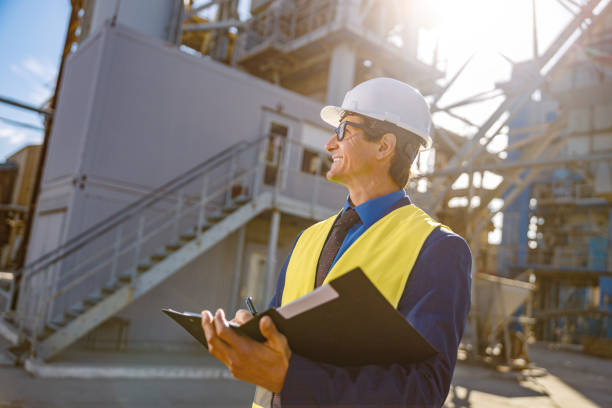 istock Cheerful male engineer doing paperwork outdoors at factory 1354697129