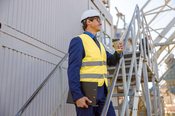istock Male factory worker holding cup of coffee and documents 1354697134