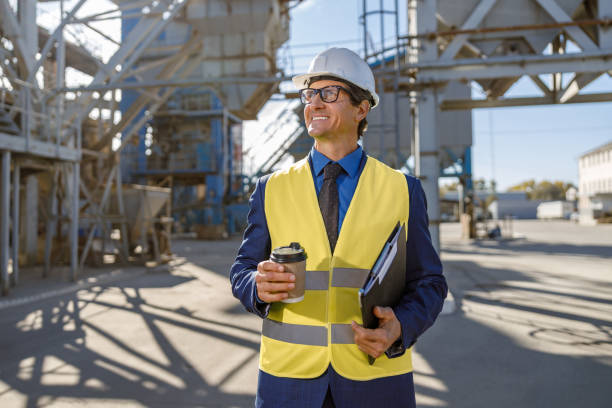istock Cheerful factory worker holding cup of coffee and documents 1354697135