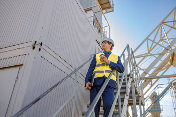 istock Male engineer with coffee cup standing on stairs outdoors 1354697145