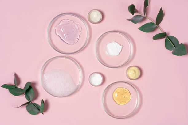 produtos cosméticos, esfoliante, soro facial e gel em muitas placas de petri em um fundo rosa. conceito de pesquisa de laboratório de cosméticos. - petri dish fotos - fotografias e filmes do acervo