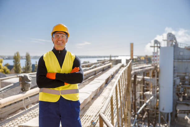 istock Cheerful male worker standing at industrial site against blue sky 1354697266