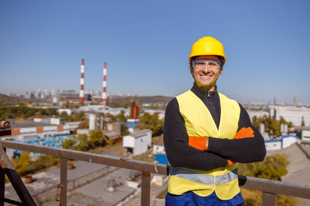 istock Joyful man factory worker standing outdoors against blue sky 1354697290