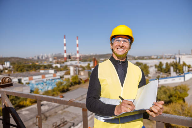 istock Cheerful male engineer with papers standing outdoors against blue sky 1354697304