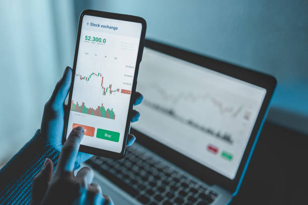 istock Trader using stock exchange app online for trading operations in mobile phone - Focus on left hand holding smartphone 1354697608