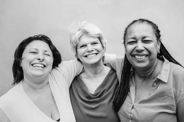 Happy diverse senior people hugging each other outdoor - Older friends community concept - Black white edition