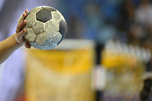 Closeup of a handballplayer holding a handball in front of a handball goal