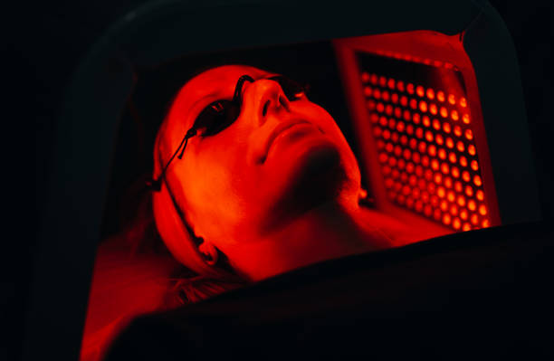 giovane donna che ha un trattamento di terapia facciale con luce led rossa in un salone di bellezza - laser therapy medical laser light therapy foto e immagini stock