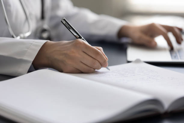 istock Female GP doctor writing medical records in workbook 1354699727