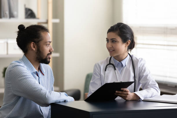 istock Young Indian general practitioner showing pad to male patient 1354699737
