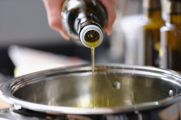 Olive oil is poured from a bottle into a saucepan, close-up. Healthy Cooking, antioxidants. Cholesterol protection