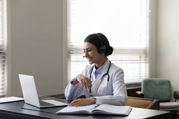istock Happy young Indian general practitioner in headphones using laptop 1354700248