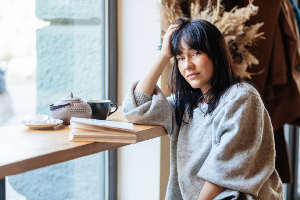 istock Young woman reading book in cafe 1354705388