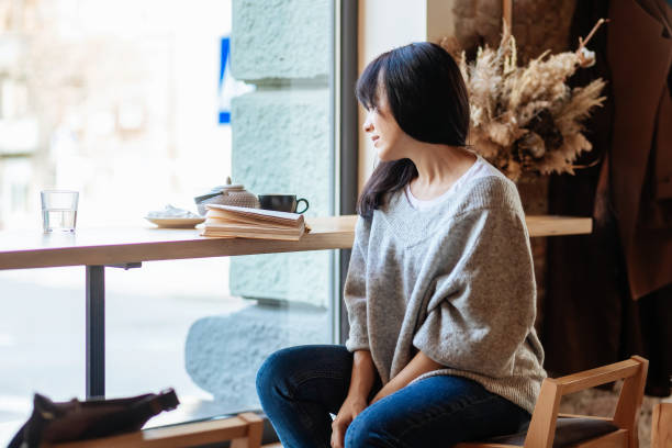 istock Young woman reading book in cafe 1354705408