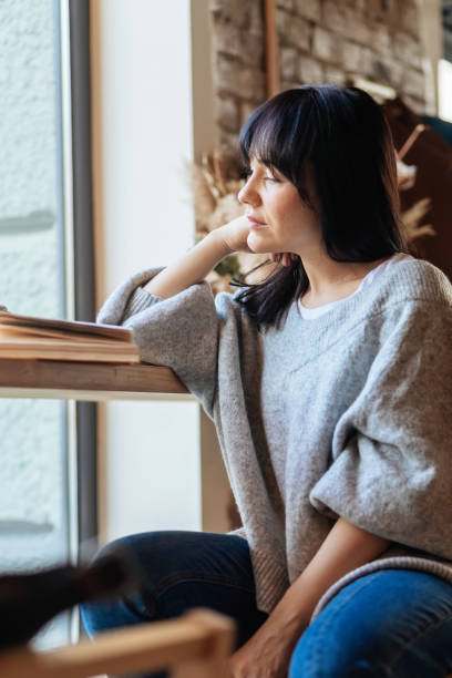 istock Young woman reading book in cafe 1354705427