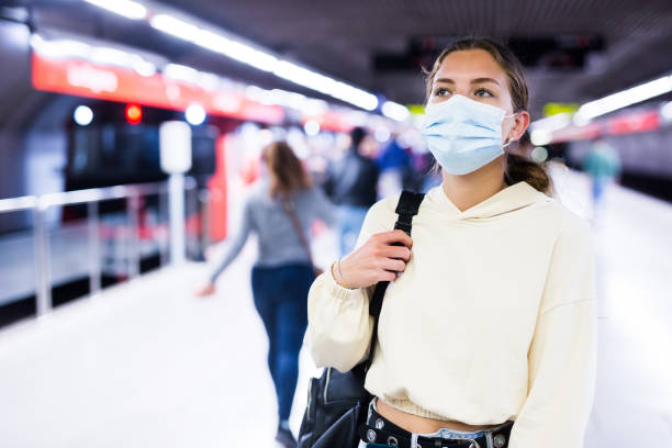 istock Young woman in face mask waiting for train 1354707720