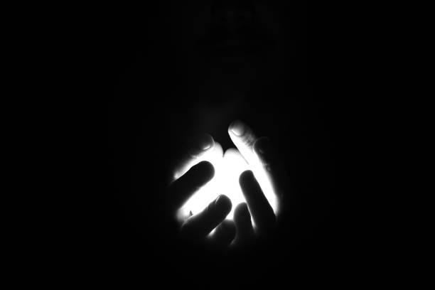 istock Hands in the dark holding the light between her fingers. 1354712763