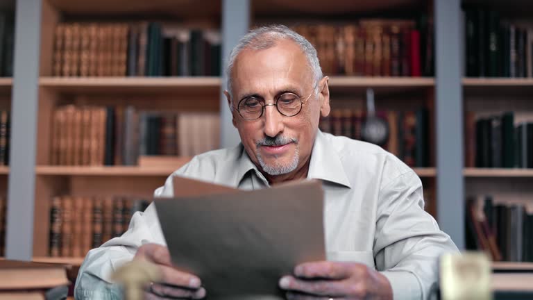 70s grandfather smiling reading paper letter good news vintage workplace in home retro library