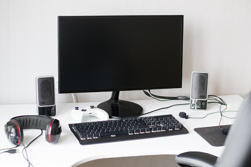 Desktop computer of gamer with black monitor, console, headphones and chair