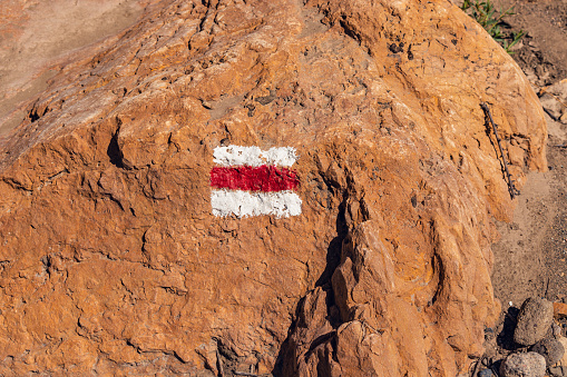 A trail marked with paint on a red stone in a desert zone. Safe hiking and recreation on the route