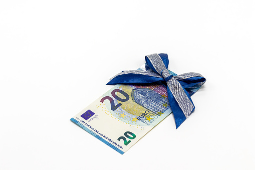 A 20 euro paper banknote decorated with a blue bow on a white background. The concept of a monetary gift, a bonus.