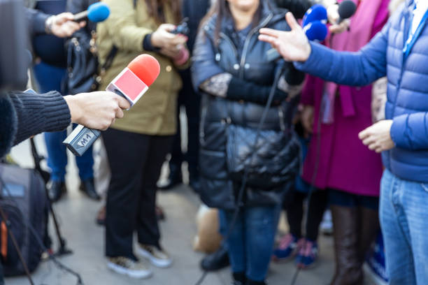 Journalists at news conference or media scrum, red microphone in the focus stock photo
