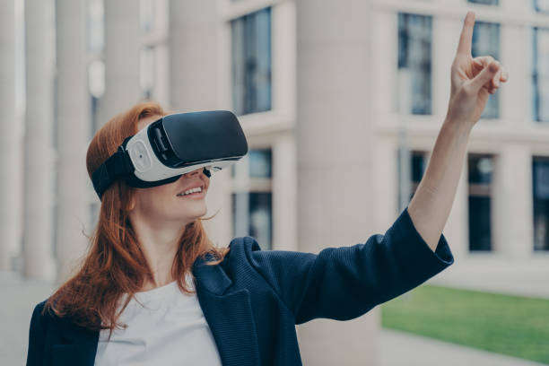 istock Happy young businesswoman using virtual reality goggles while standing outdoors 1354731495