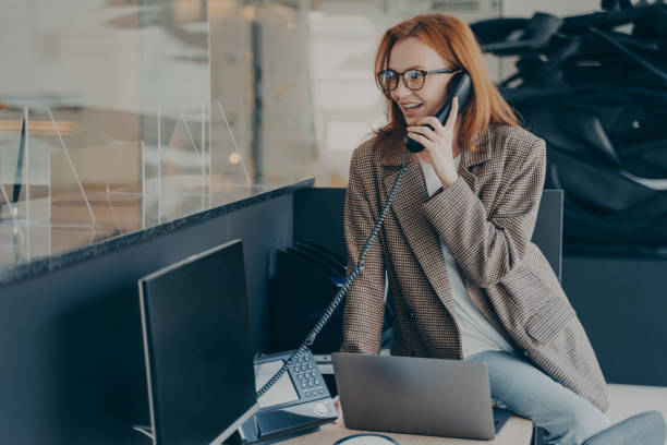 istock Woman in spectacles talking on phone while sitting at her workplace in office 1354731500