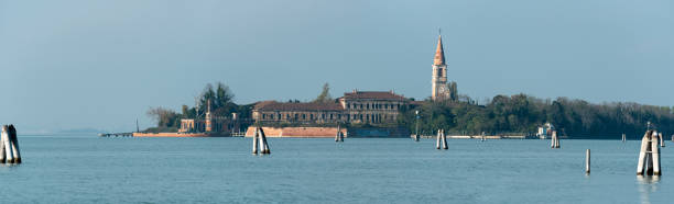 вид из лидо на заброшенный остров повелья, бывшую психиатрическую больницу венеции - lido стоковые фото и изображения
