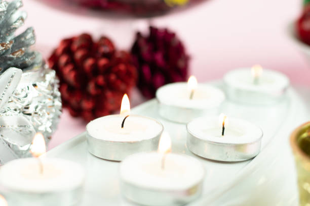 istock White Tealight Candles Illuminated In Row With Maroon Pine Cone Glitter Decorations On Light Pink Background. Theme For Merry Christmas And Happy New Year 1354736154