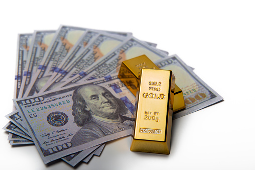 Examples of American currency dollar and gold bullion. Dollars and gold bars on a white background.
