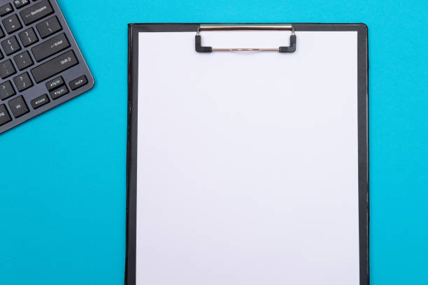 istock Black Clipboard with Sheet of Paper on Blue Table 1354736764