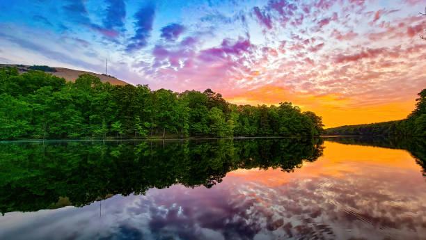 Colorful sunrise over Stone mountain park reflected in still lake stock photo