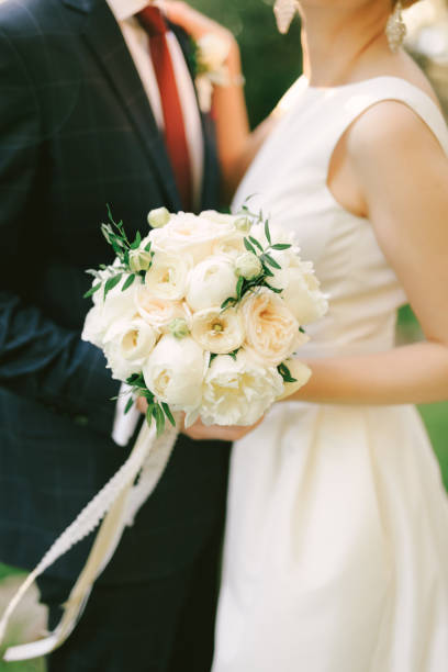 青い市松模様のスーツを着た花婿は、花束を持つ白いドレスを着て花嫁を抱きしめる。クローズ アップ - bride caucasian wedding ceremony close up ストックフォトと画像