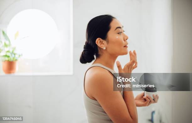 Morning Routine Attractive Asian Woman Applying Face Cream In Her Home Stock Photo - Download Image Now
