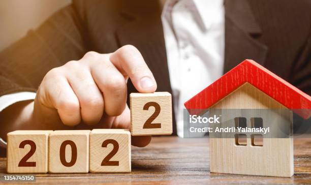 A Businessman Making 2022 Out Of Blocks Near House Concept Of The Real Estate Market In The New Year Forecast Of Prices And Offers New Trends And Tendencies Investment Plans Mortgage Loan Stock Photo - Download Image Now