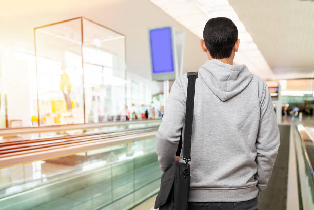 jeune homme debout sur une passerelle en mouvement à l’aéroport - entrance hall flash photos et images de collection