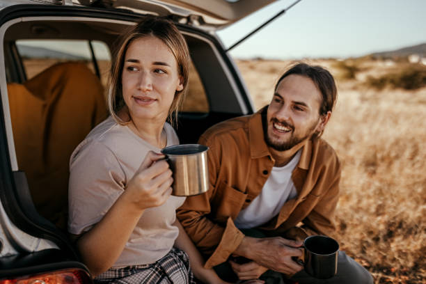 istock Young couple drinking coffee in car trunk 1354752109
