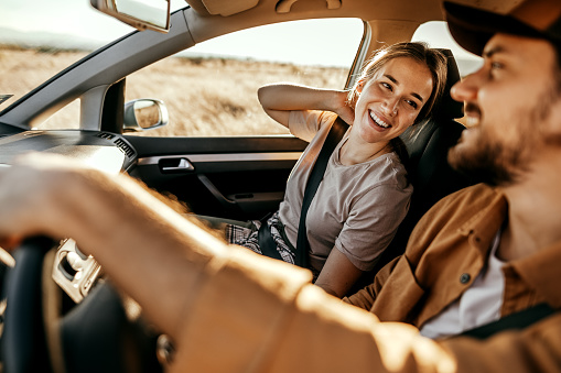 Cheerful couple having fun while driving through rural field on road trip